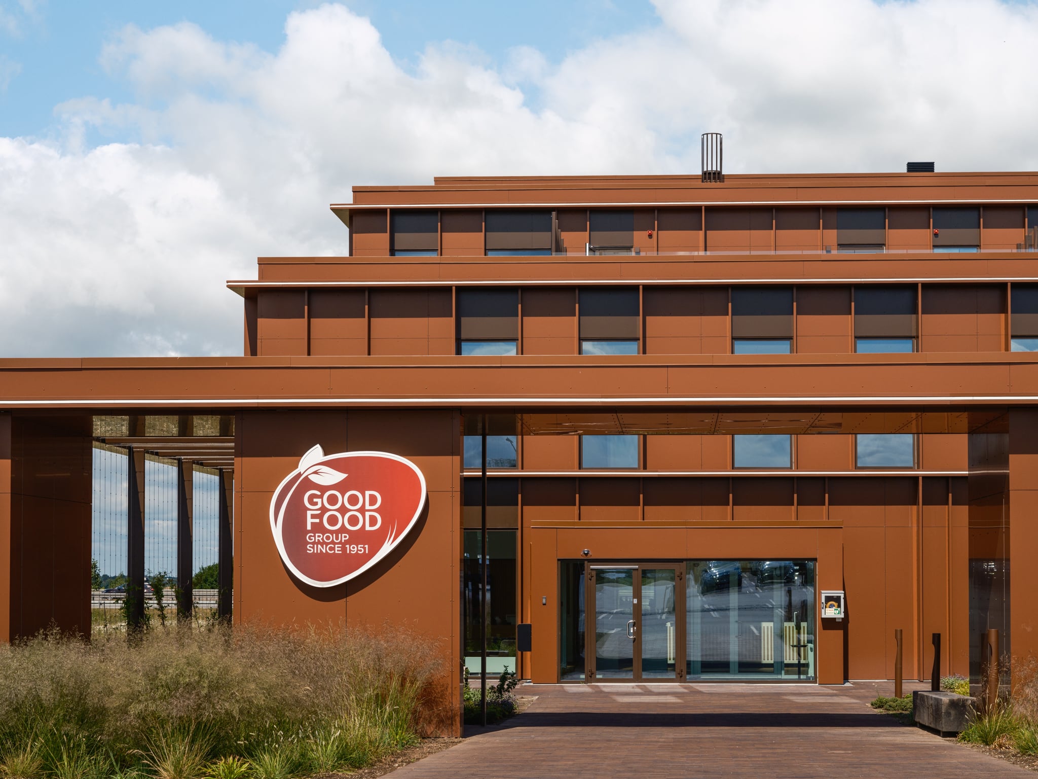 Billedet viser  indgangsfacaden hos Good Food Group i Vejle. Domicilet ligger ud til E45 og er i flere etager. Facaden er udført i 6000 m2 Aluminium komposit plader Etalbond. Arkitekterne er Arkitema.